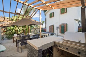 Une terrasse extérieure équipée d’un barbecue, d’un coin salon et d’une table de billard.