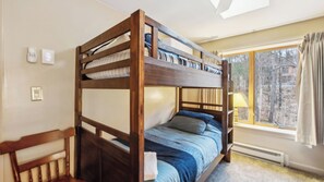 Dormitorio con literas, ventana, lámpara y termostato.