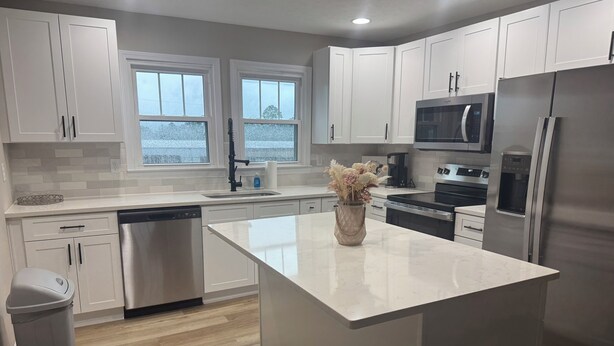 A modern kitchen with white cabinets, stainless steel appliances, and a central island. - Close to SRP park the medical district and Fort Gordon (North Augusta)
