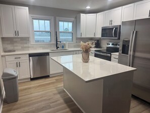 Een moderne keuken met witte kasten, roestvrijstalen apparatuur en een centraal eiland.