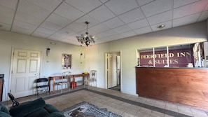 Zona de recepción con escritorio, sillas, una lámpara de araña y un cartel de Deerfield Inn & Suites.