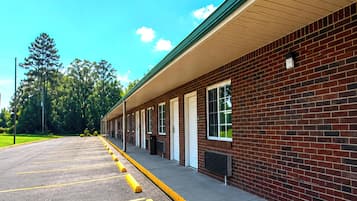 A row of single-story brick buildings with a covered walkway and a parking lot.