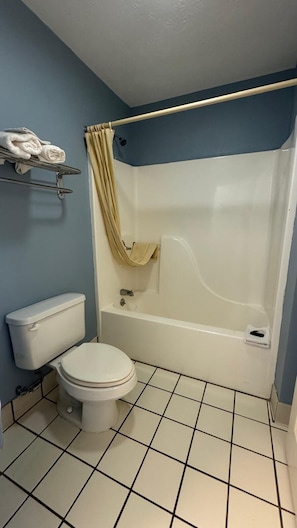 A bathroom with a toilet, bathtub, and a towel rack with folded towels.