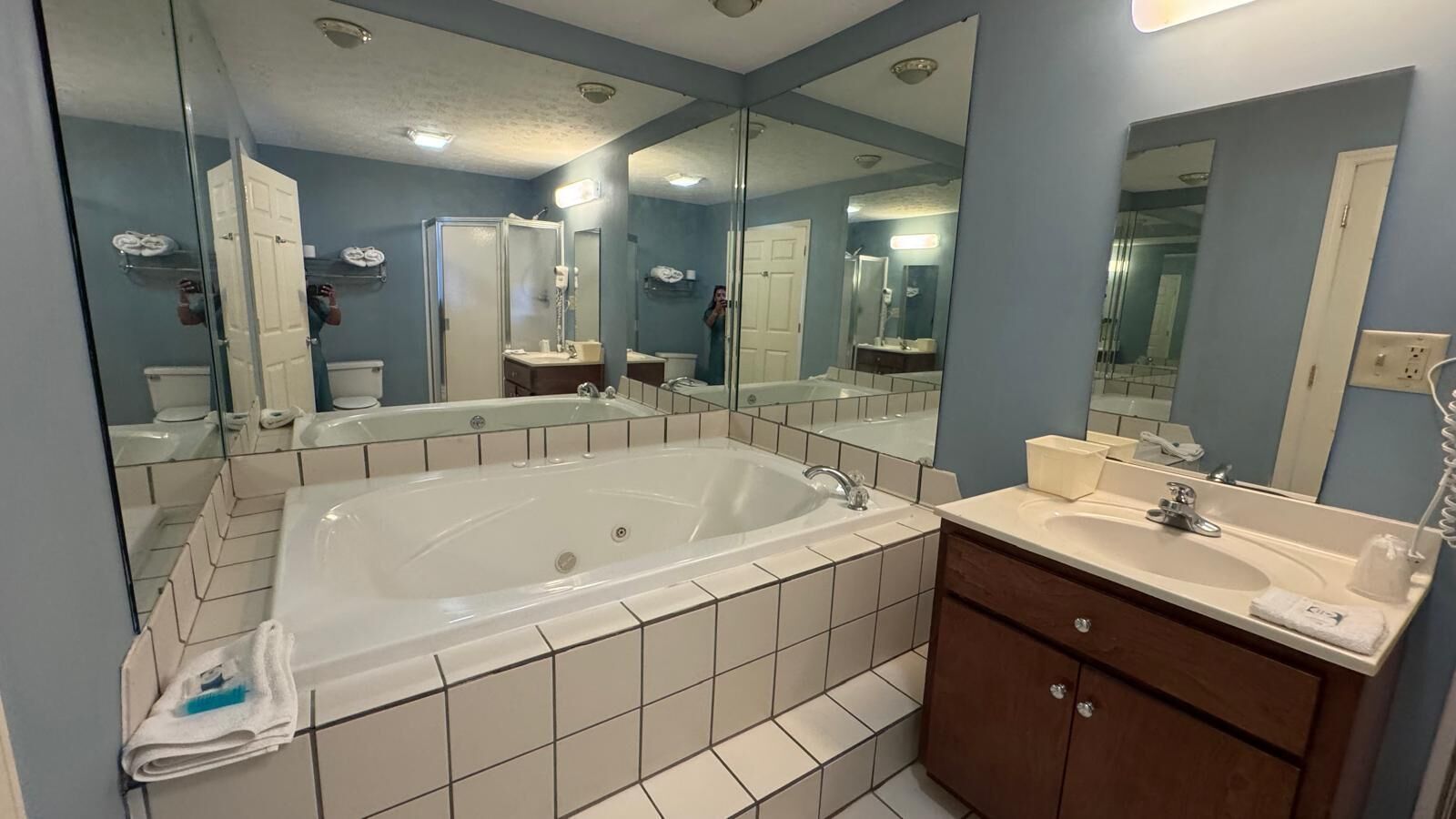 A bathroom with a large bathtub, a vanity with a sink, and a mirror.