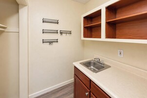 Una cocina con un lavamanos empotrado, armarios de madera y toalleros metálicos en la pared.