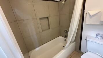 A bathroom with a bathtub, toilet, and shower curtain.