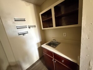 Una pequeña cocina con un lavamanos, armarios y una ventana sobre la encimera.