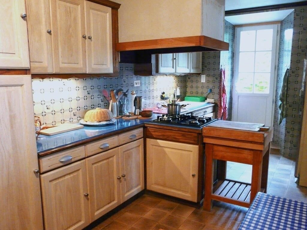 Una cocina compacta con armarios de madera, cocina a gas y una pequeña encimera.