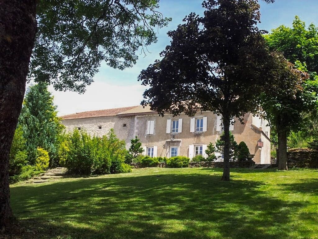 Un grand bâtiment doté d’un toit en tuiles, entouré d’une pelouse bien entretenue et d’arbres.