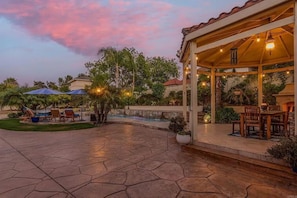 A covered patio area with outdoor furniture, a pool, and a garden. - The Estate Pool Spa and Bounce House (Vista)