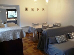 Una habitación con cama, sofá, mesa de comedor y sillas, además de un ventanal.