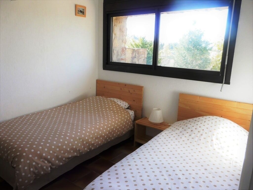 A room with two single beds, a window, and a small bedside table with a lamp.