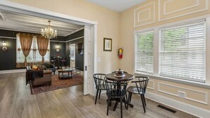 A spacious living room with a dining area, hardwood floors, and a large window with blinds.