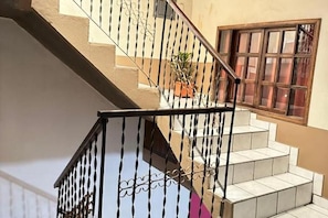 Uma escadaria com corrimão de metal, um vaso de planta e uma janela com vários painéis.