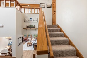 A staircase with wooden railings and carpeted steps leading to a living area with a sofa and a coffee table. - Secluded Townhome 15 min from Downtown (Galena)