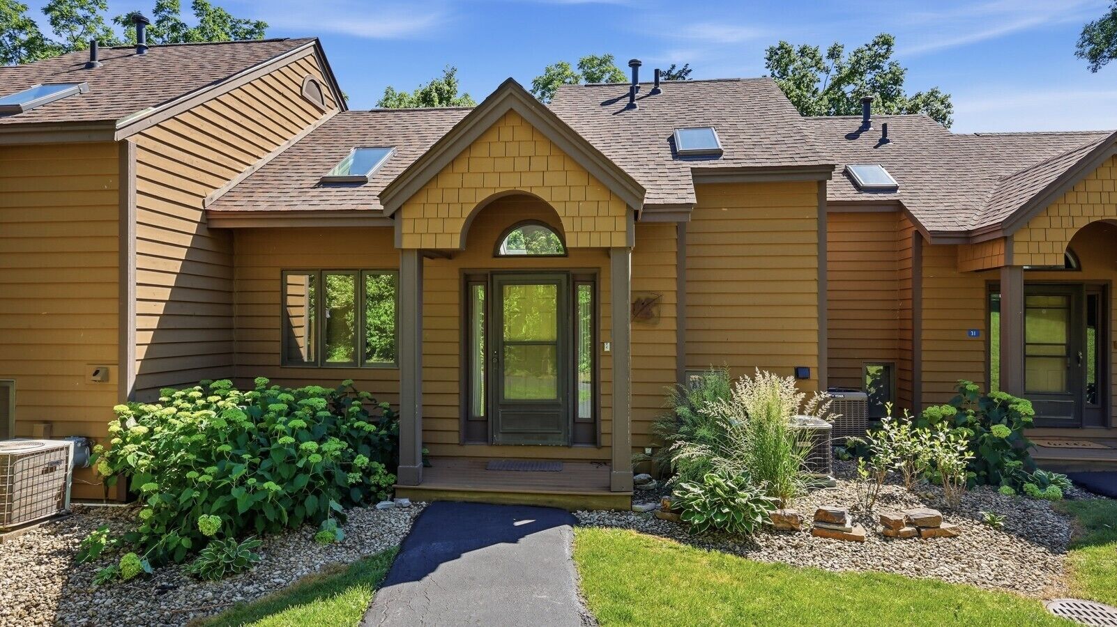 A two-story house with a front entrance, a covered porch, and a small garden area.