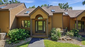 A two-story house with a front entrance, a covered porch, and a small garden area. - Secluded Townhome 15 min from Downtown (Galena)