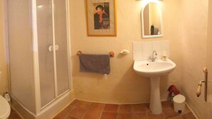 Ein Badezimmer mit Toilette, Dusche, Waschbecken und einem an der Wand hängenden Handtuch.