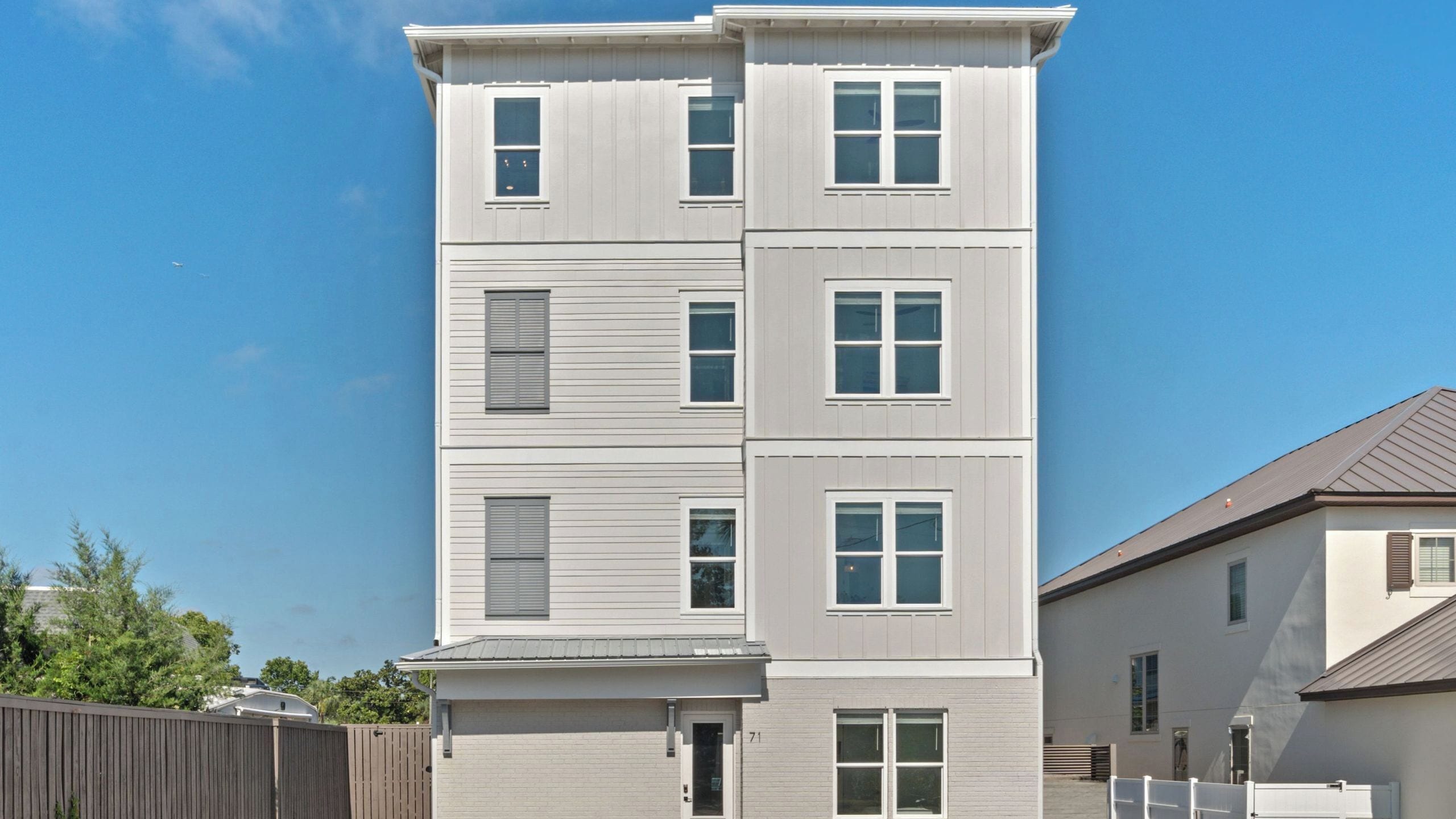 A multi-story residential building with a flat roof, multiple windows, and a visible door.