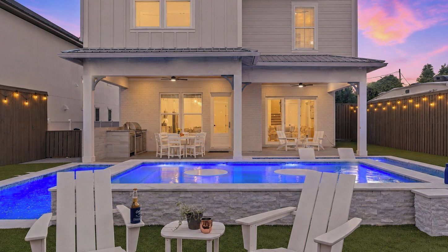 Ein zweistöckiges Haus mit Swimmingpool, Außenbereich zum Sitzen und einer Terrassenfläche.