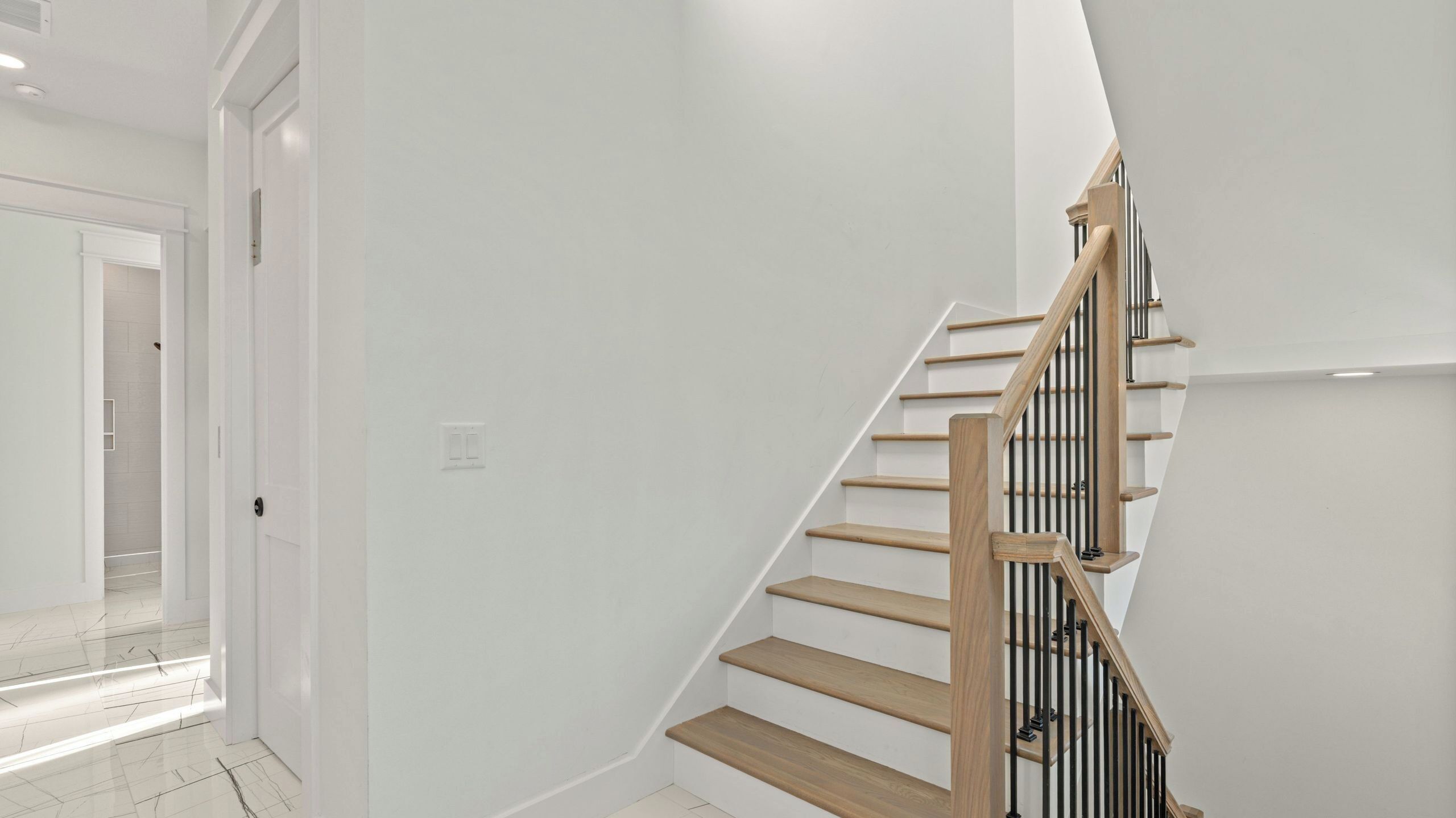 A staircase with wooden steps and black railings, leading to an upper floor.