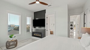 Ein modernes Schlafzimmer mit Kamin, Fernseher und einem großen Bett.