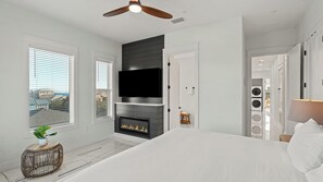 Ein modernes Schlafzimmer mit Kamin, Fernseher und einem großen Bett.
