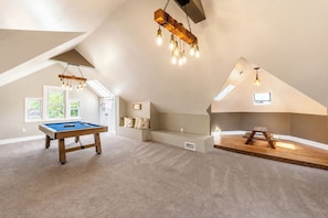 A spacious loft with a pool table, a wooden bench, and a loft bed.