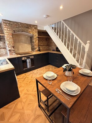 Een moderne keuken met een bakstenen muur, houten vloer en een eethoek voor vier personen.