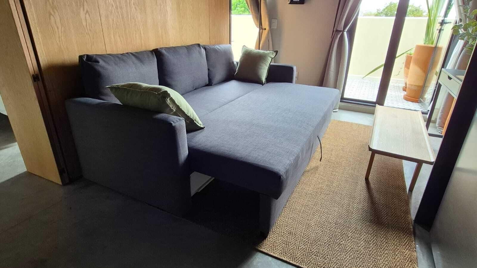Una habitación moderna con sofá, una mesita y vistas a través de un ventanal.