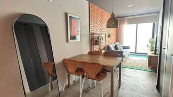 A modern dining area with a brick accent wall, a wooden dining table, wicker chairs, and a hanging pendant light.