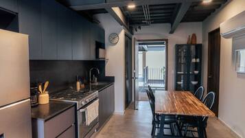 A modern kitchen with a central island, a dining table with chairs, and a view to a balcony.