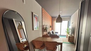 Un salon moderne comprenant un coin repas, un grand miroir et un mur d’accent en briques.