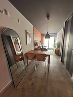 Una sala de estar moderna con comedor, un espejo grande y una pared decorativa de ladrillo.