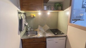 A compact kitchen with wooden cabinets, a dishwasher, a sink, and a window. - Studio with private bathroom for 4 people at the base of the gondola (Cauterets)