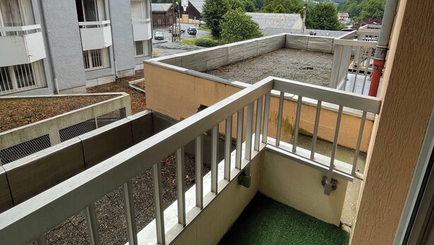 A balcony with a view of a mountainous landscape, a building with multiple balconies, and a small patch of artificial grass. - Studio with private bathroom for 4 people at the base of the gondola (Cauterets)
