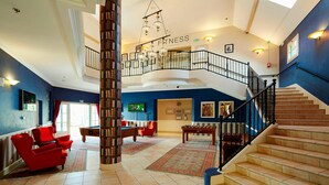 A spacious lobby with a central column, a staircase, and a fitness area.