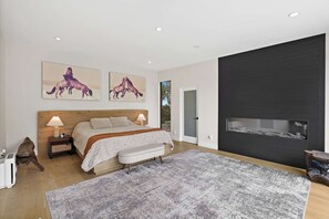 Ein Schlafzimmer mit einem Bett, Nachttischlampen, einer Bank, einem Teppich und zwei Bildern von Pferden an der Wand.