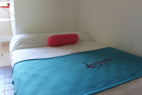 Un lit simple avec un matelas blanc et une couverture de couleur turquoise.