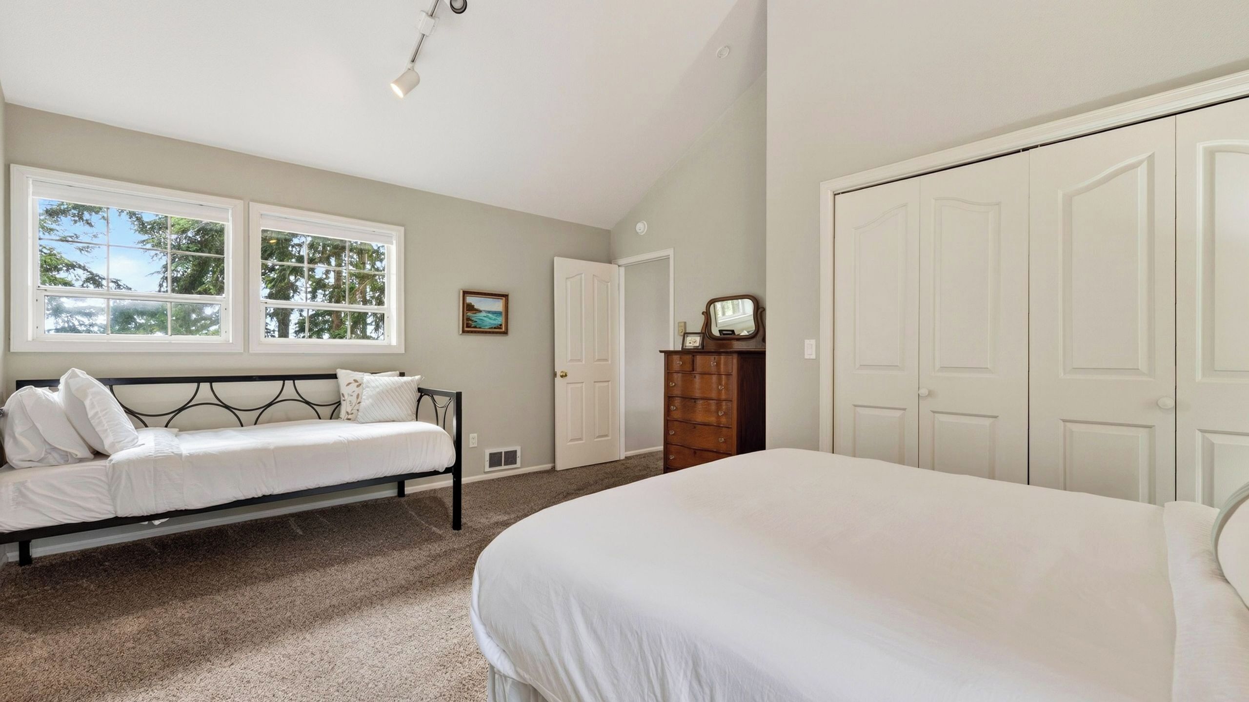 A bedroom with a bed, a bench, a dresser, a door, and a window.
