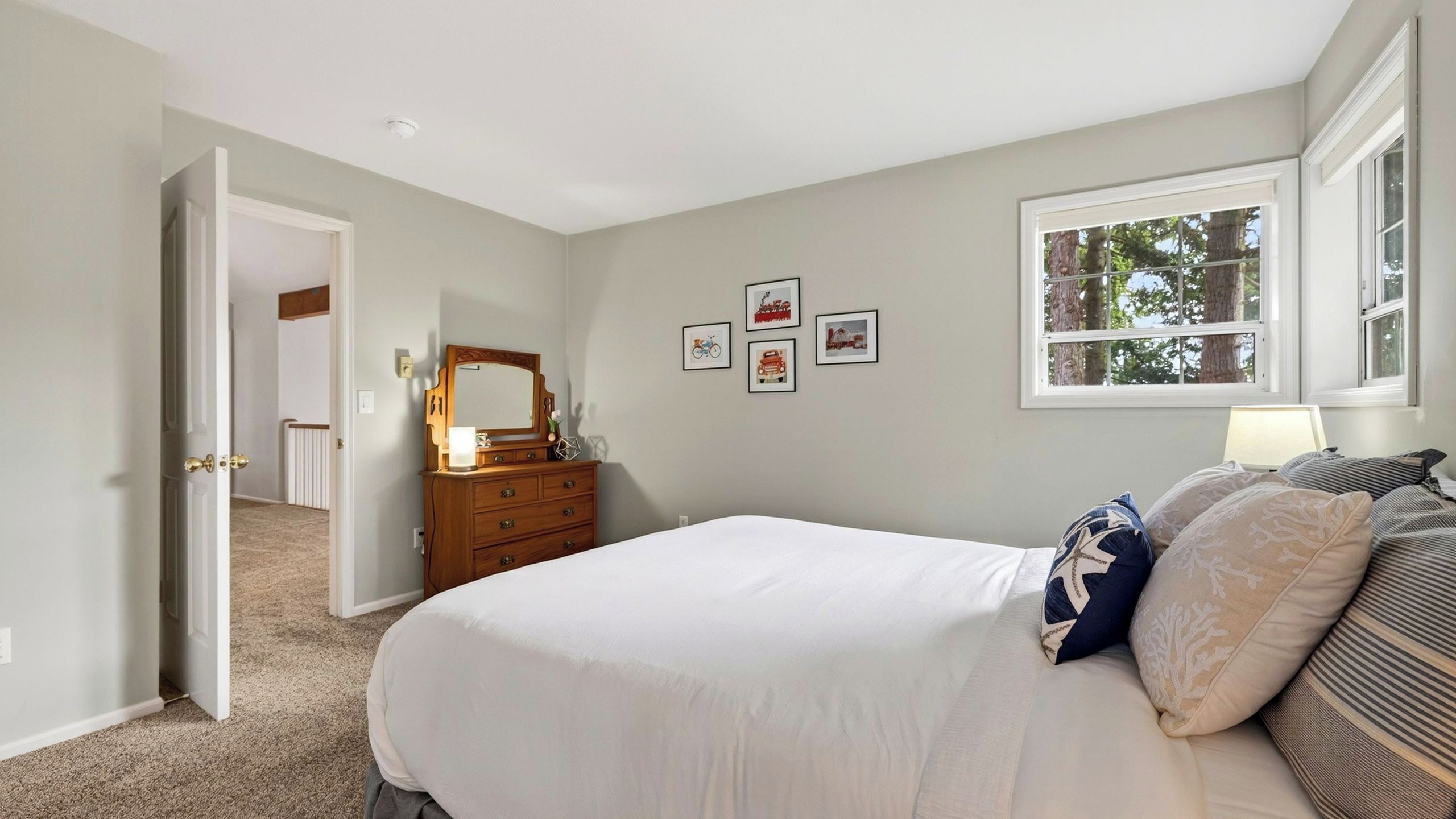 A bedroom with a bed, dresser, and a window.