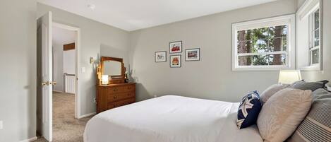 A bedroom with a bed, dresser, and a window.