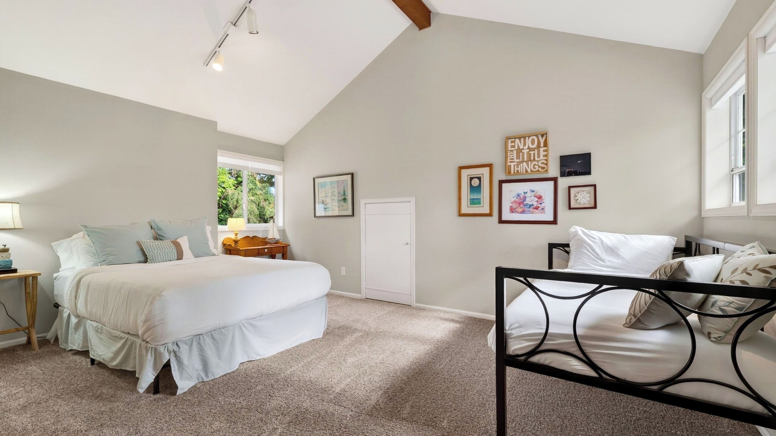 A bedroom with two beds, a window, and wall art.