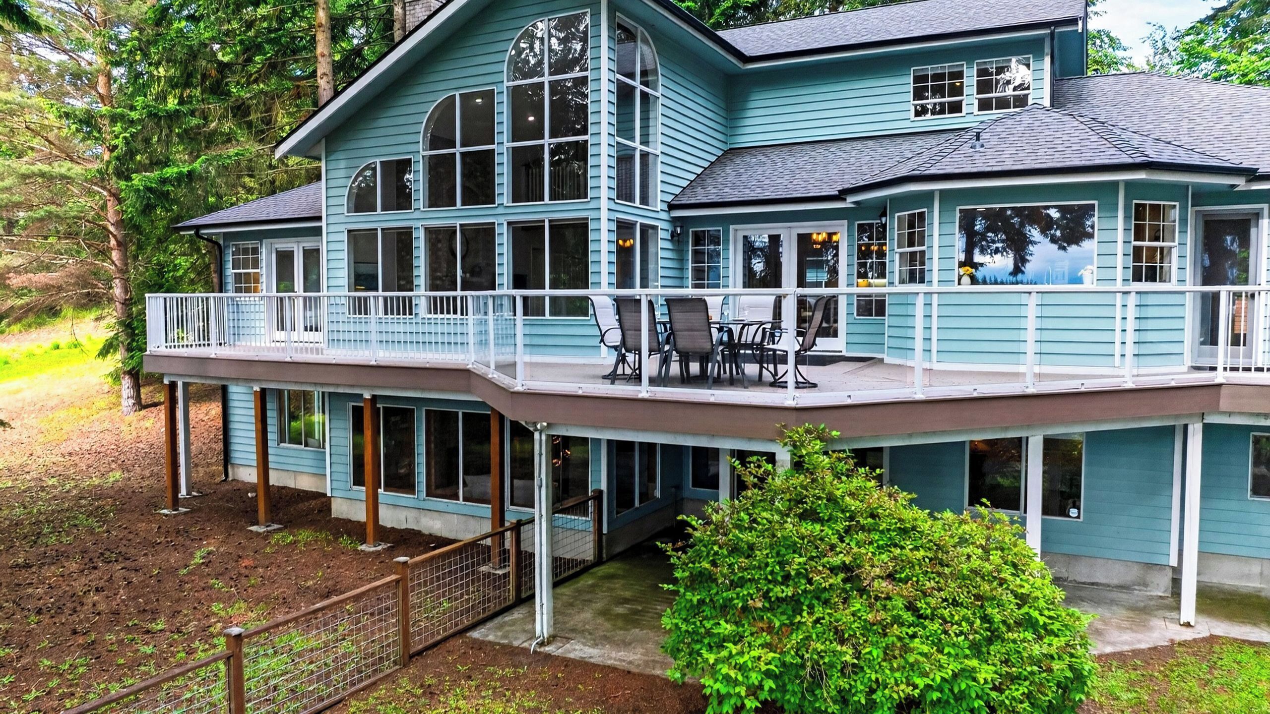 A large two-story house with a balcony, large windows, and a covered porch area.