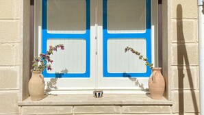 Ett fönster med två vita paneler och blå kanter, omgivet av två keramikkrukor med blommor.