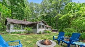 A house with a fire pit and blue chairs in a garden. - Secluded Mid-Century Haven | Hot Tub | Fire Pit (Fennville)