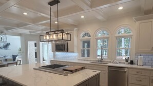 A modern kitchen with a large island, white cabinetry, and a built-in microwave.