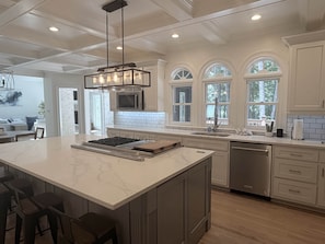 A modern kitchen with a large island, white cabinetry, and a built-in microwave.