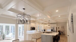 A spacious kitchen with white cabinetry, a central island, and a dining area with a round table and chairs.