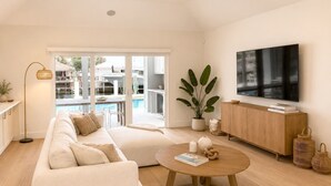 Una sala de estar moderna con sofá, mesa de centro, televisor y vistas a una piscina y zona exterior.